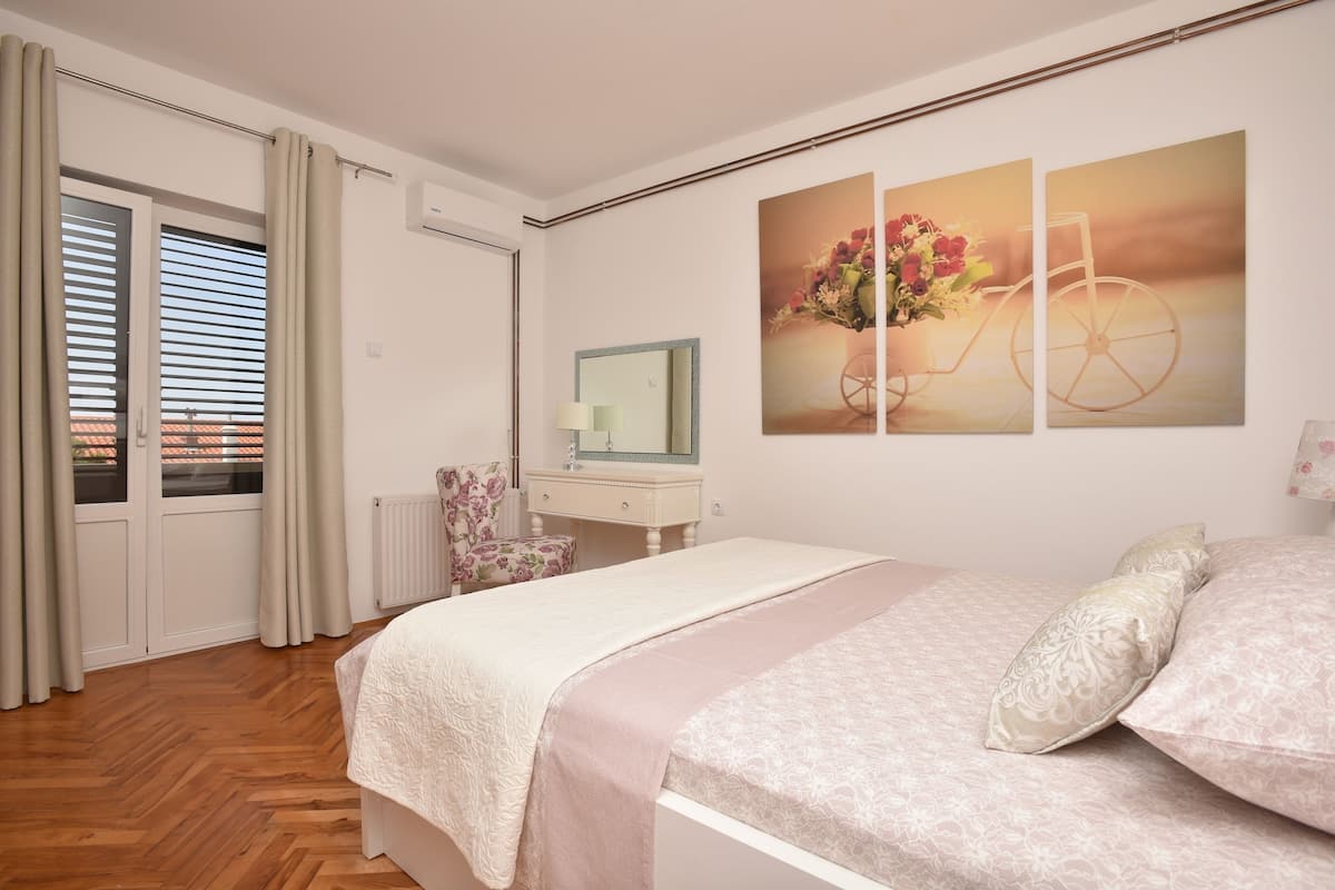 A bedroom with a bed, a dresser, a mirror, and a window with blinds.