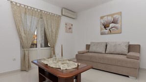 En stue med en beige sofa, et træbord og et stort blomsterbillede på væggen.