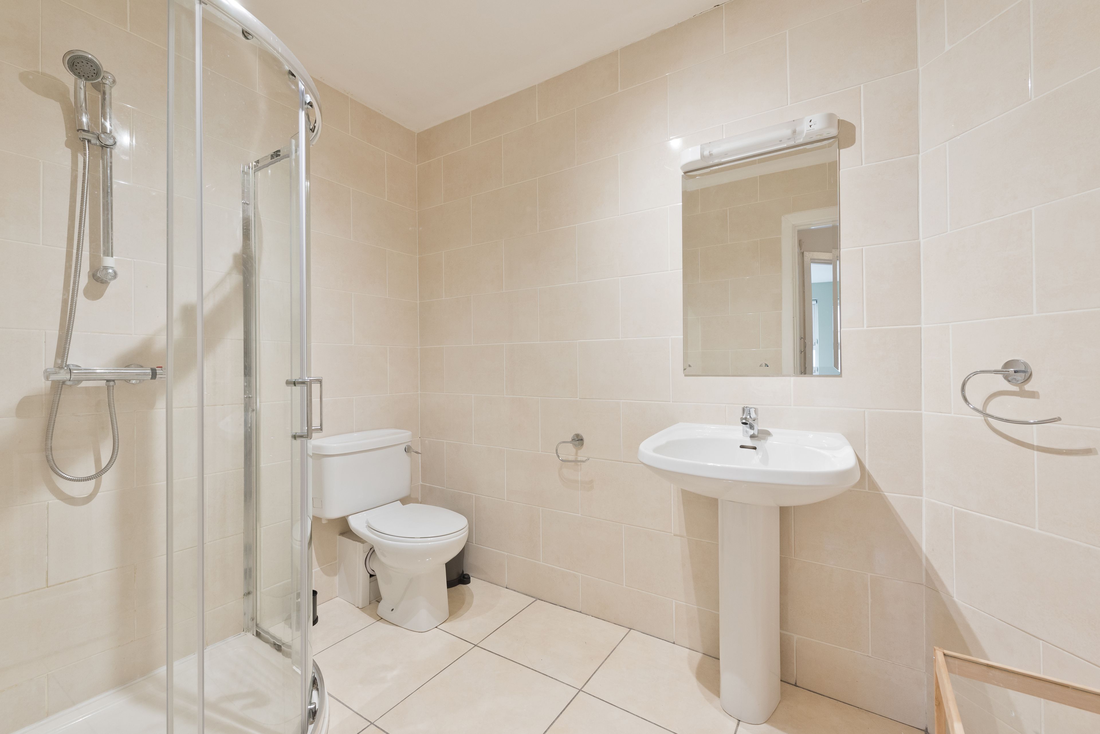 A modern bathroom with a glass shower enclosure, a toilet, and a pedestal sink.
