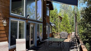A wooden deck with outdoor seating, a covered patio, and large windows. - Beautiful Mountain Home Near Yosemite (Groveland)