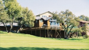 A two-story house with a deck, surrounded by trees and a grassy area. - Beautiful Mountain Home Near Yosemite (Groveland)