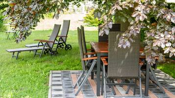 An outdoor patio with a table and chairs under a tree.