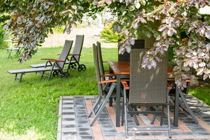 An outdoor patio with a table and chairs under a tree. - Treppendorfer Apartments (Burgebrach)