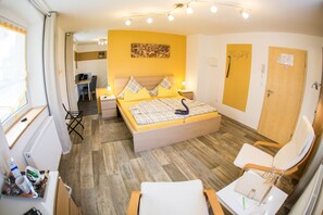 A bedroom with a bed, bedside tables, a desk, and a chair. - Treppendorfer Apartments (Burgebrach)