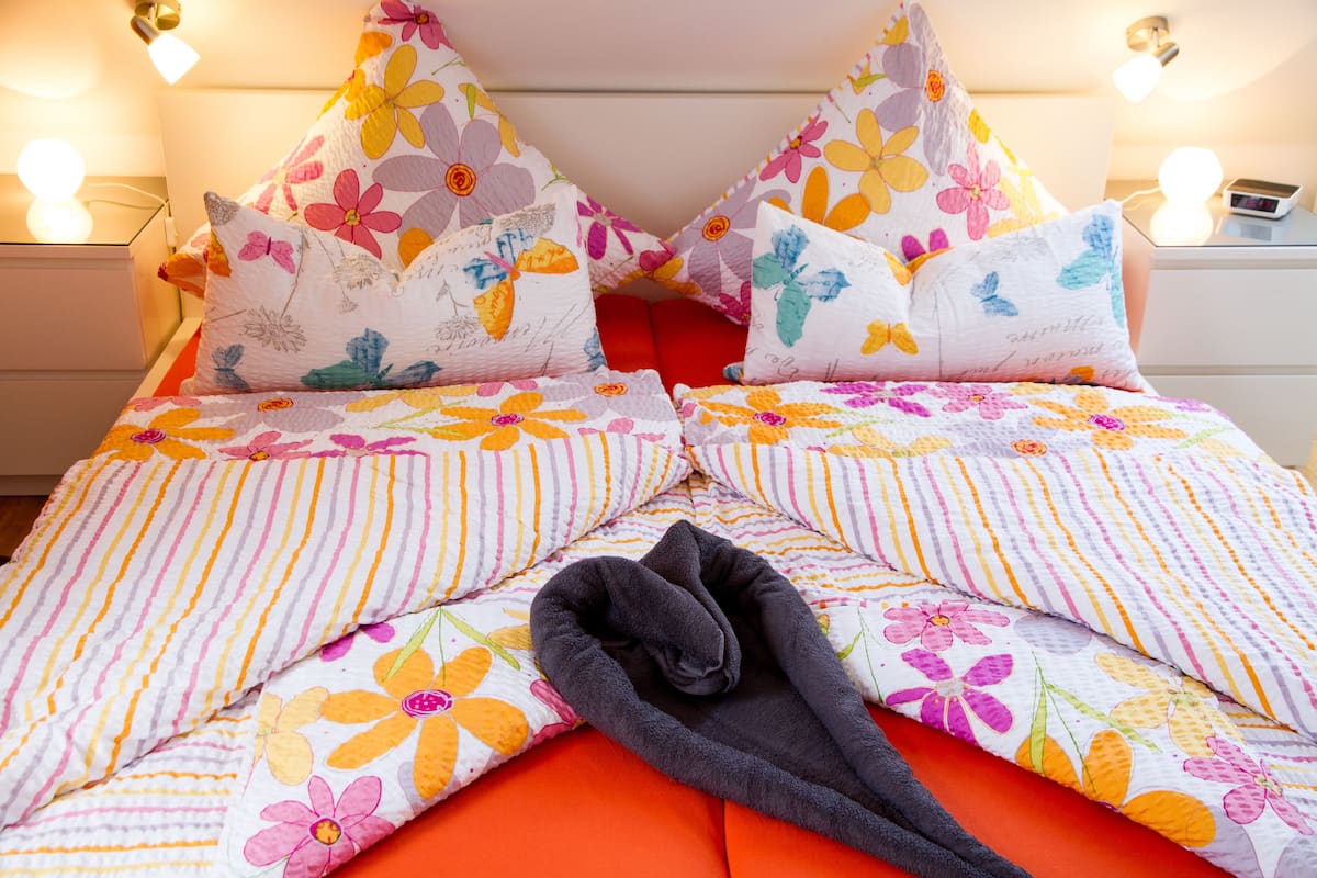 A bed with floral bedding and a black towel.