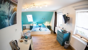 Ein Schlafzimmer mit Bett, Nachttischen, Schreibtisch, Stuhl, Heizkörper und Fenster.