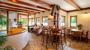 A rustic interior with exposed wooden beams, stone flooring, and a bar area with stools. - Landhotel Gut Wildberg (Klipphausen)