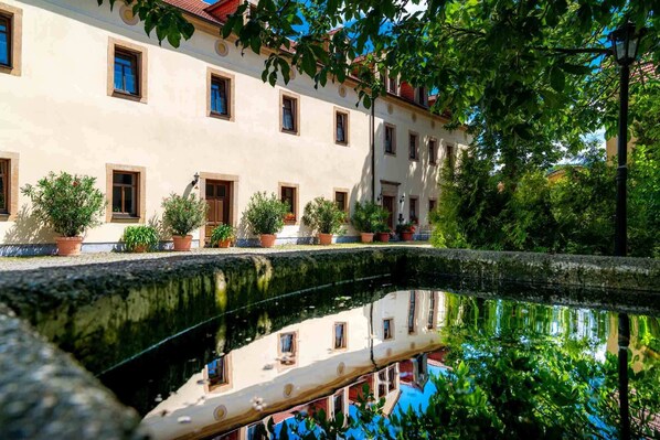 A building with multiple windows and potted plants in front. - Landhotel Gut Wildberg (Klipphausen)