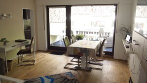 A modern apartment with a dining area, a kitchen, and a balcony with a view. - Ferienwohnung AltesSalzwerk (Bad Harzburg)