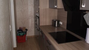A modern kitchen with a built-in oven, a stovetop, and a microwave. - Ferienwohnung AltesSalzwerk (Bad Harzburg)