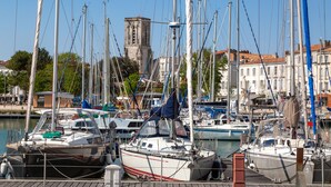 A marina with multiple boats docked, a prominent tower in the background, and buildings along the waterfront. - Hôtel La Tour de Nesle La Rochelle Vieux Port (La Rochelle)