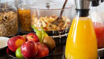 Un buffet de petit-déjeuner comprenant des fruits, du granola et du jus d’orange.