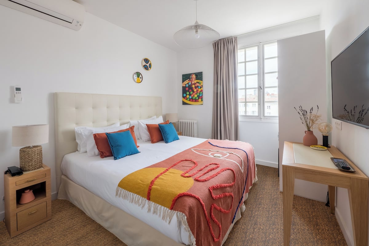 Une chambre d’hôtel moderne, dotée d’un grand lit, de tables de chevet, d’un bureau et d’une télévision.