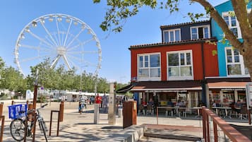 A street with a Ferris wheel, a red building with a café, and a blue building with a restaurant.