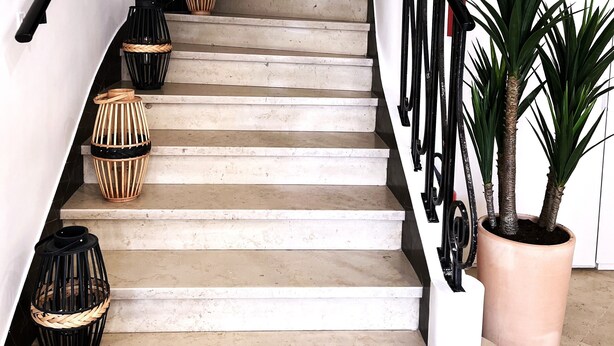 A staircase with a black handrail, beige steps, and decorative wicker baskets. - Hôtel La Tour de Nesle La Rochelle Vieux Port (La Rochelle)