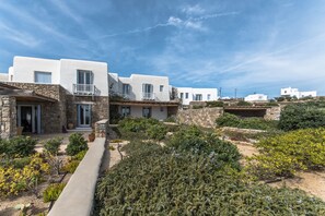 Un edificio blanco con detalles de piedra, un sendero de piedra y varios arbustos y plantas.