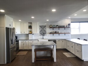 A modern kitchen with white cabinets, a marble countertop, and a built-in dishwasher. - Casa Tranquila Puerto Nuevo with Ocean and Mountain View that Sleeps 20 (Puerto Nuevo)