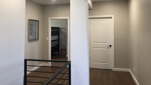 A hallway with a staircase, a white door, and a framed picture on the wall. - Casa Tranquila Puerto Nuevo with Ocean and Mountain View that Sleeps 20 (Puerto Nuevo)