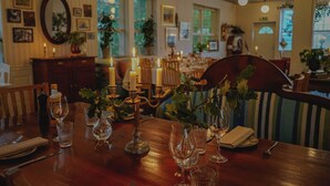 A dining area with a wooden table set for a meal, candles, and potted plants. - Turistgården - House Of Ven (Sankt Ibb)