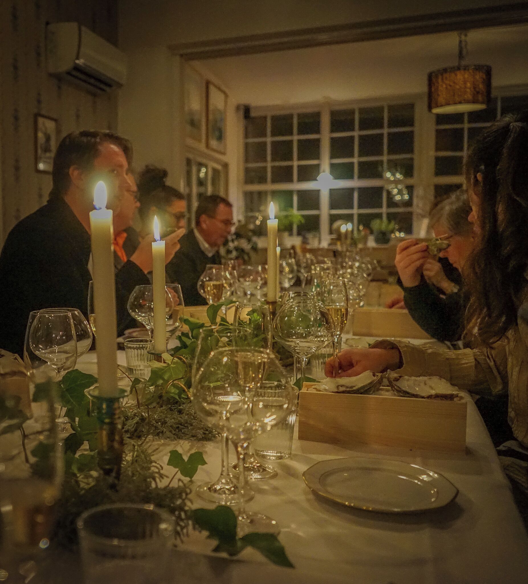 A formal dining table set with candles, wine glasses, and plates, suggesting a restaurant or banquet setting.