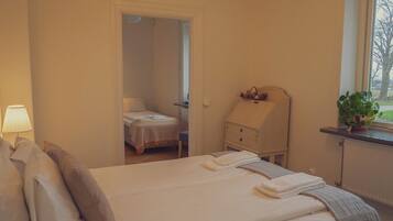 A bedroom with a bed, bedside table, lamp, and a window with a plant.
