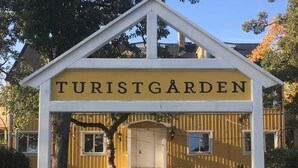 A building with a sign reading "TURISTGÅRDEN" and a covered entrance with steps leading up to it. - Turistgården - House Of Ven (Sankt Ibb)