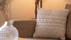 A cozy living room with a lamp, a cushion, and a decorative vase on a wooden table. - Grichting Hotel & Serviced Apartments (Leukerbad)