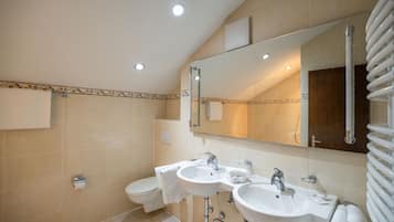 Un baño moderno con dos lavamanos, un inodoro y un espejo grande.