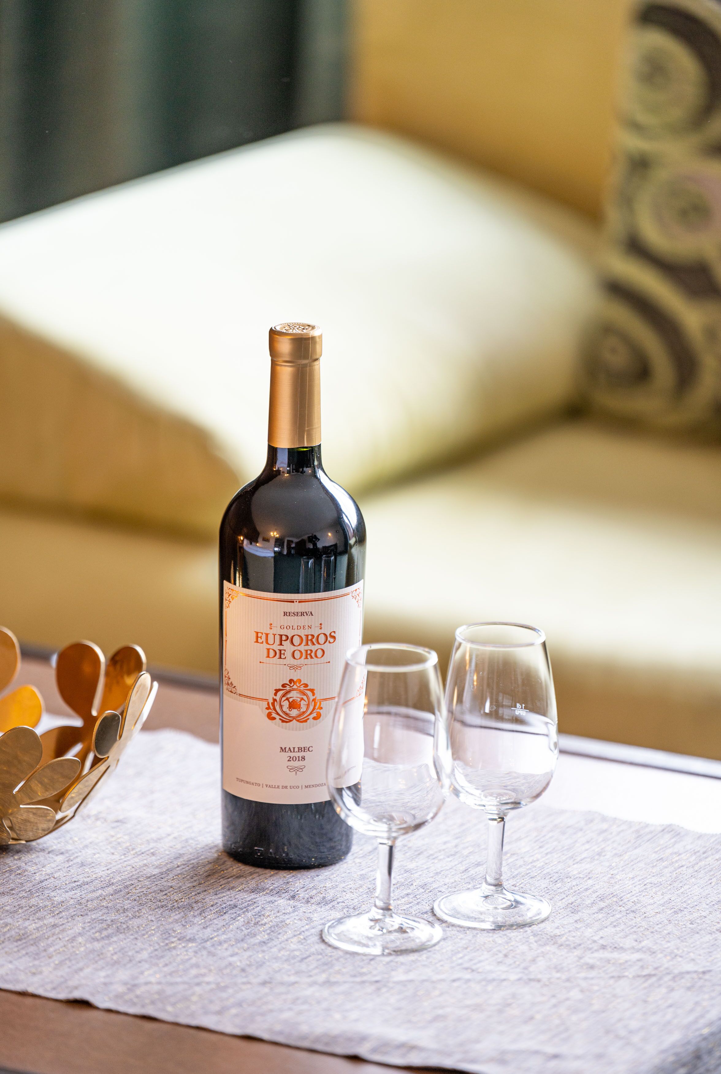 A bottle of EUPOROS DE ORO wine with two glasses on a table.