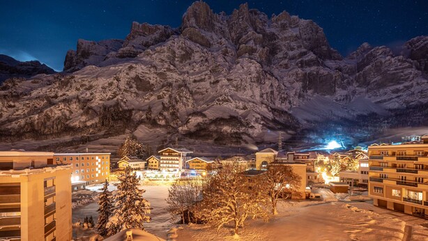 A snow-covered mountain range at night with illuminated buildings in the foreground. - Grichting Hotel & Serviced Apartments (Leukerbad)