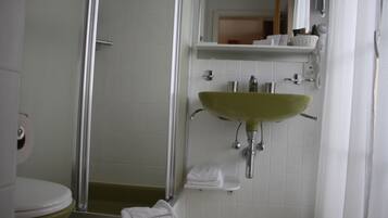 A bathroom with a shower, toilet, sink, and a mirror.