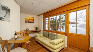 Una habitación acogedora con una mesa de madera, un sofá y una ventana con vista nevada.