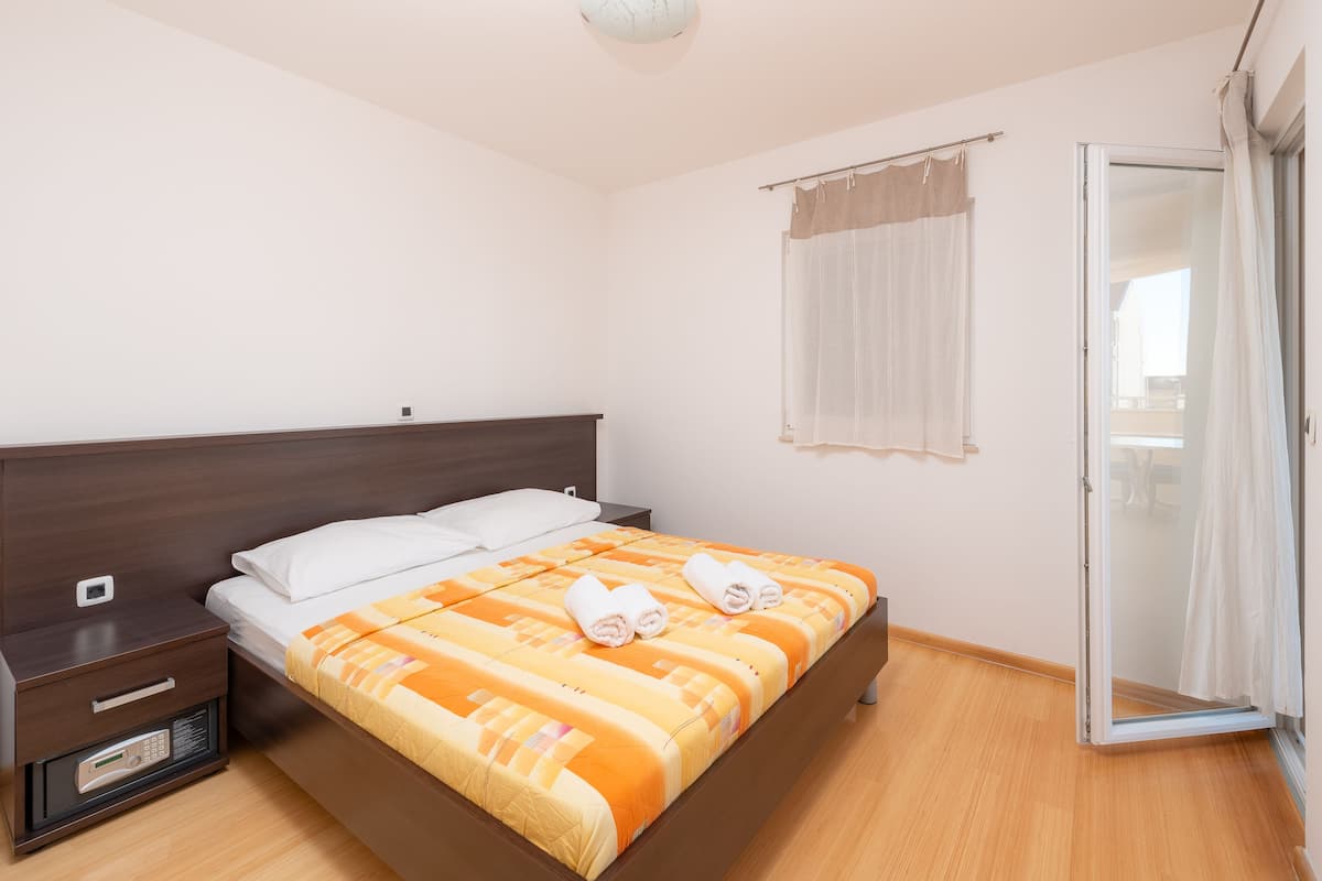 Ein Schlafzimmer mit Bett, Nachttisch und einer Schiebetür zum Balkon.