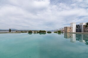 Una piscina cristalina con un muro de piedra y un edificio moderno al fondo.