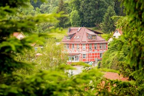 A red and white building with a sloped roof, surrounded by lush greenery.