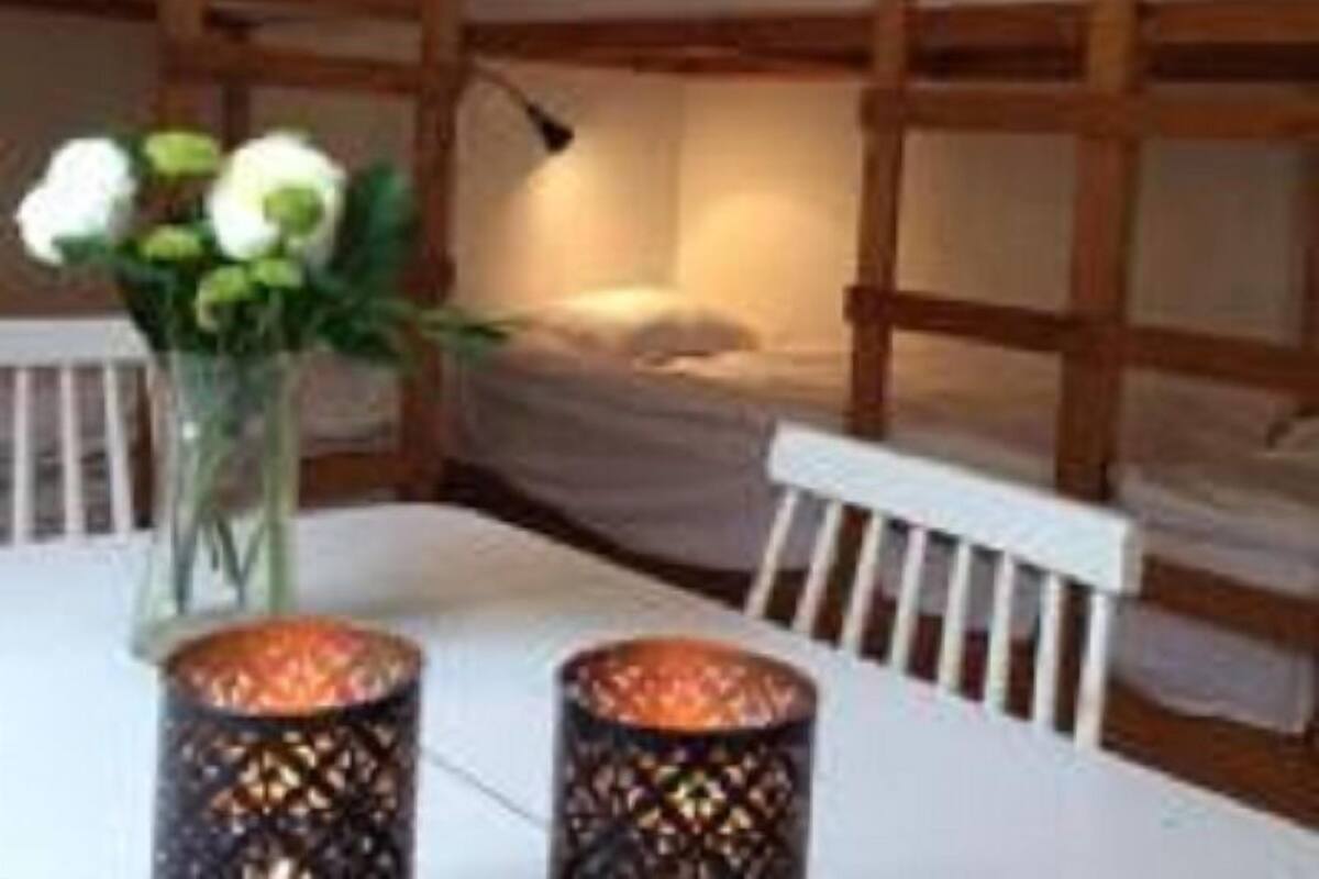 A bunk bed room with a table and chairs, a vase with flowers, and two decorative lanterns.