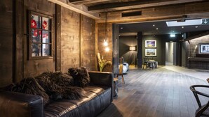 Un interior moderno con un sofá de cuero, paredes de madera y un comedor con mesa y sillas.