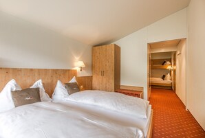 Una habitación de hotel con una cama grande, cabecero de madera y un pasillo cubierto de alfombra roja.