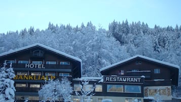 A hotel and restaurant with a snowy forest backdrop.