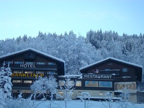 Experience the charm of BANKLIAP's traditional chalet-style hotel and adjacent restaurant, set amidst a serene mountainous backdrop.