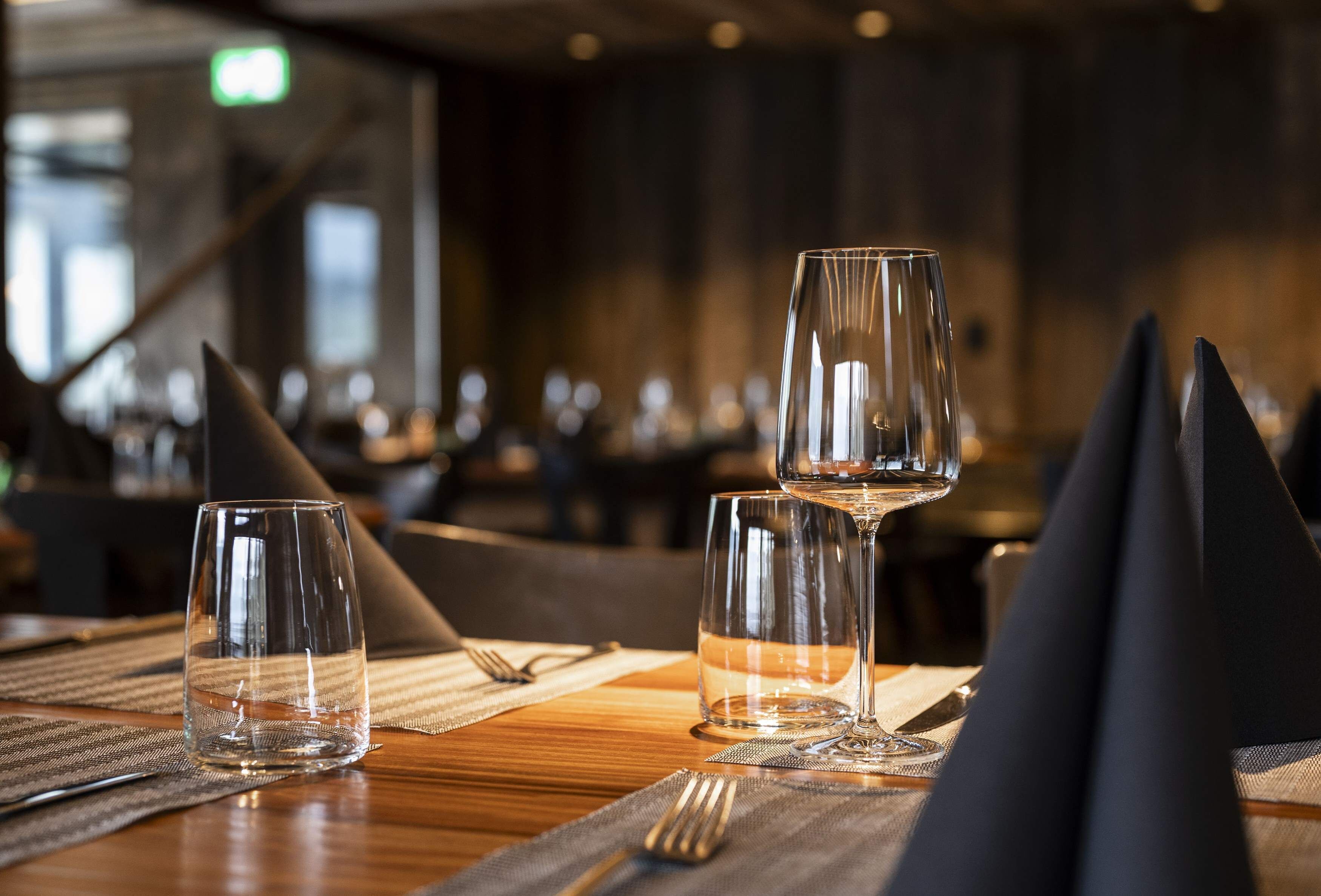 A dining table with three wine glasses and a black napkin.