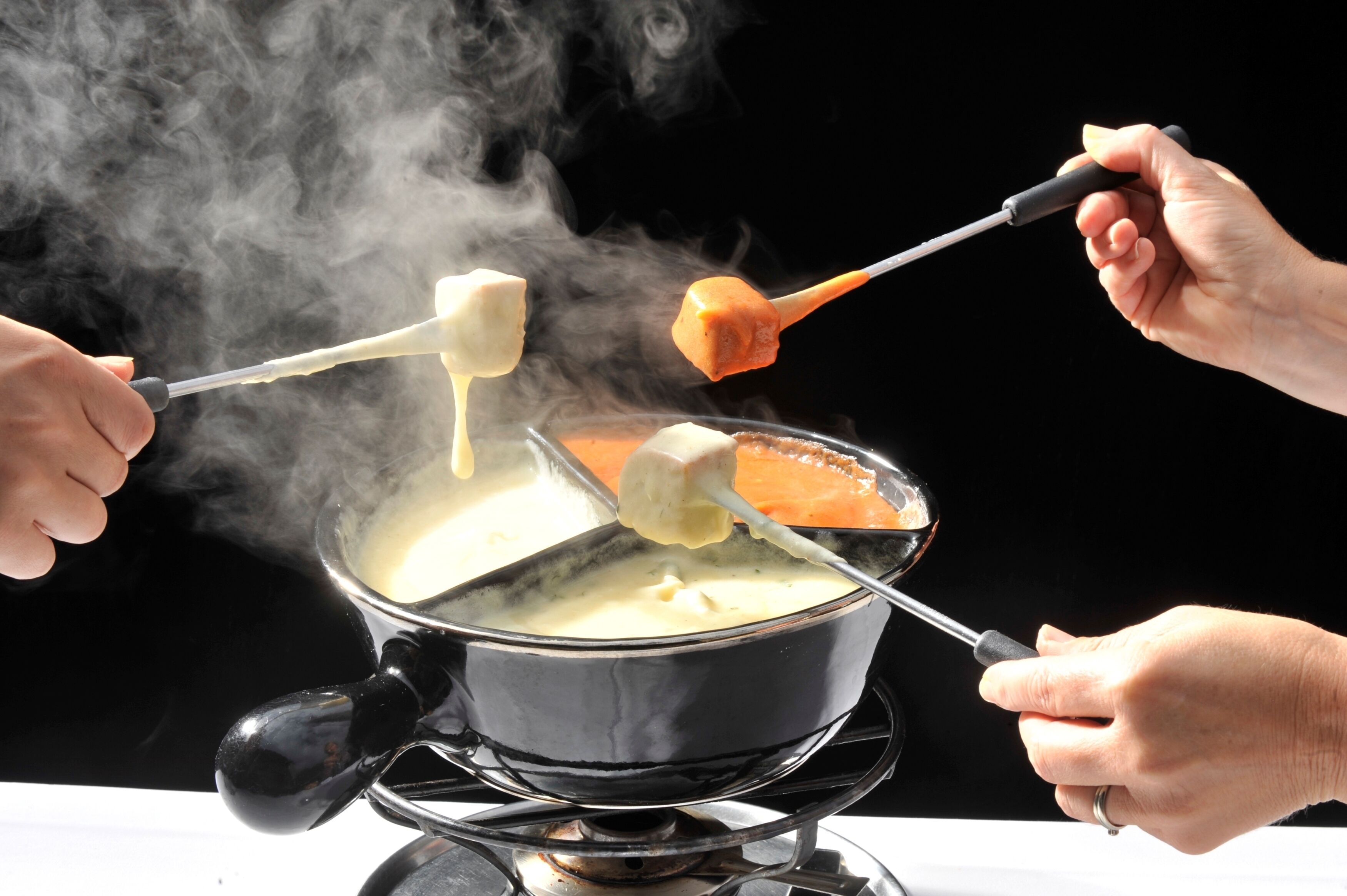 A person holding a ladle with a piece of food over a pot of boiling liquid.
