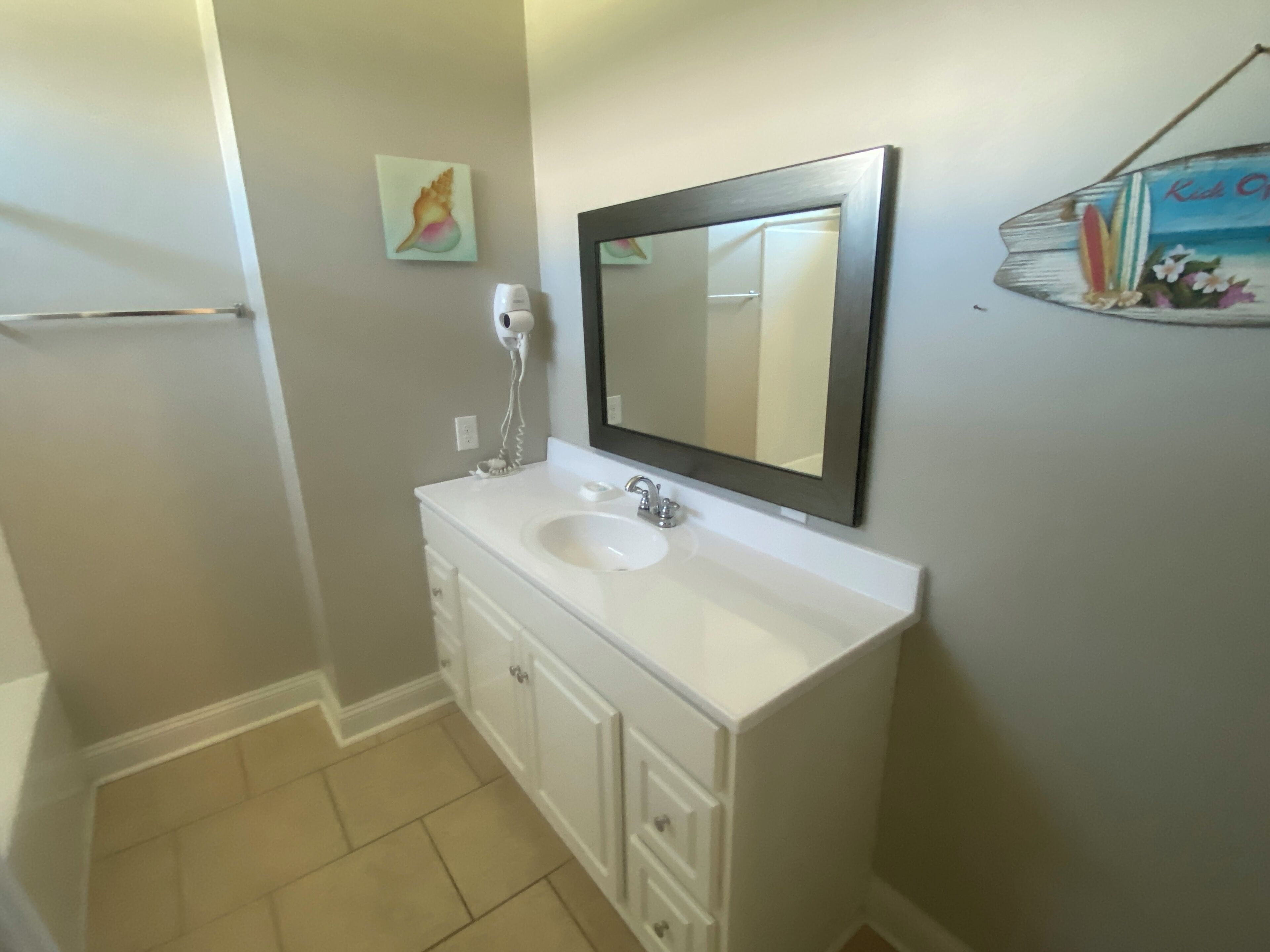 A bathroom with a white sink, a mirror, and a towel rack.