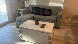 A living room with a sofa, a coffee table with a plant, and a lamp on a side table. - RAISED BEACH HOUSE 1 BLOCK FROM BEACH (Myrtle Beach)