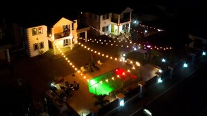 A hotel courtyard with outdoor seating and a pool area, surrounded by buildings with balconies and string lights. - Candice serviced Apartment (Sunyani)