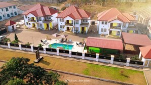 A residential complex with multiple houses, a swimming pool, and a fenced garden area. - Candice serviced Apartment (Sunyani)