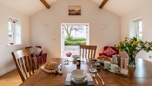 Un coin repas avec une table en bois mise pour le petit-déjeuner, comprenant du pain, des viennoiseries et du café.