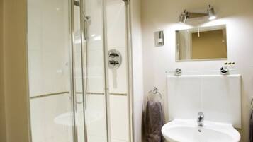 Un baño con cabina de ducha de vidrio, un lavabo y un espejo sobre él.