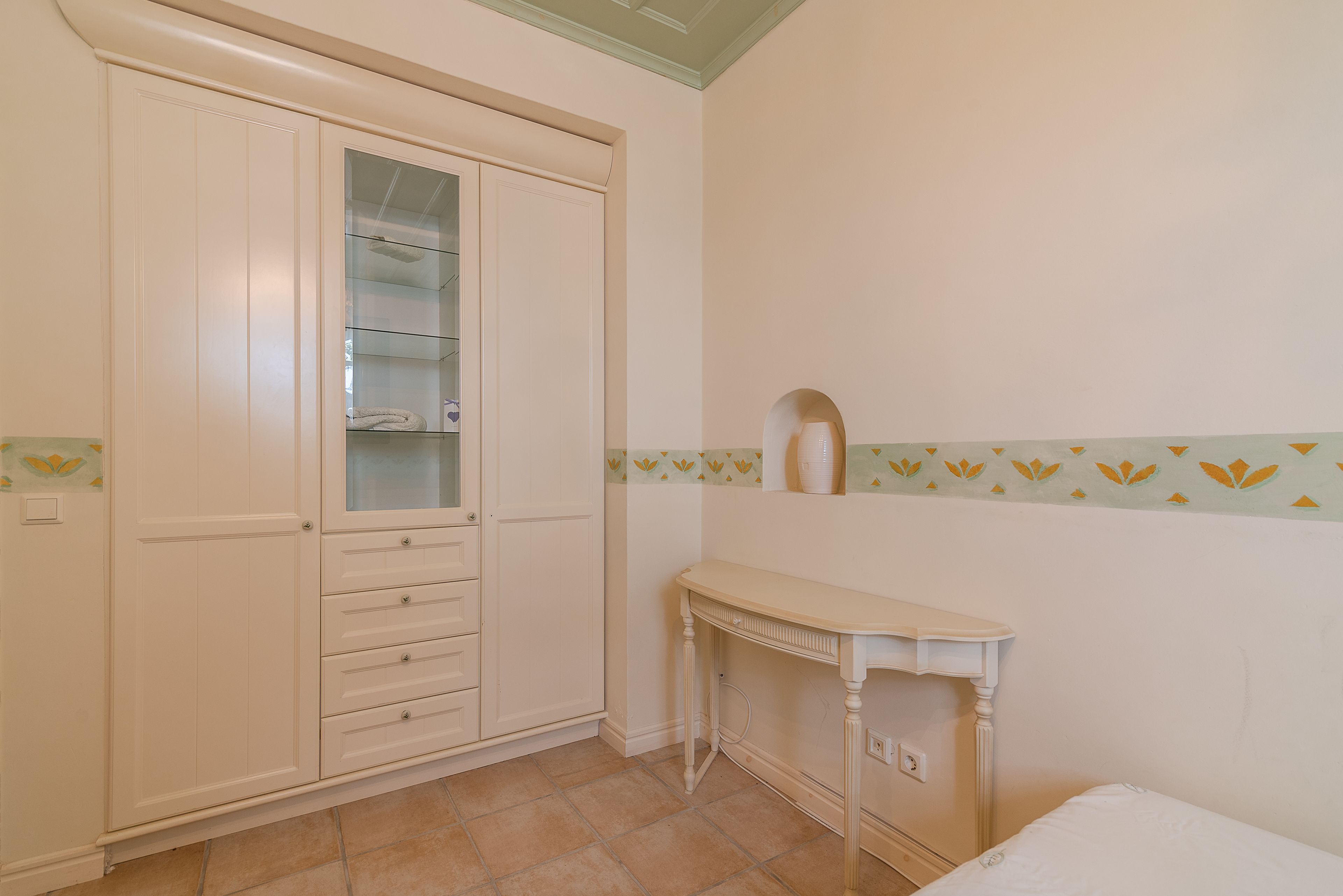 A bedroom with a bed, a bedside table, a wardrobe, and a mirror.