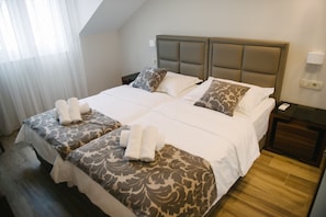 Una habitación de hotel con una cama grande, dos mesitas de noche y una mesita auxiliar.